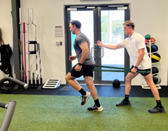 An exercise physiologist at Inertia Health Group assists a client with resistance-based exercises, f